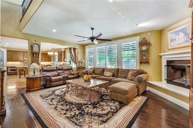 living room featuring ceiling fan with notable chandelier and dark hardwood / wood-style floors