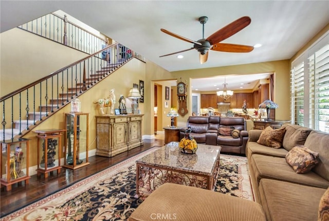 living room featuring ceiling fan with notable chandelier and dark hardwood / wood-style floors