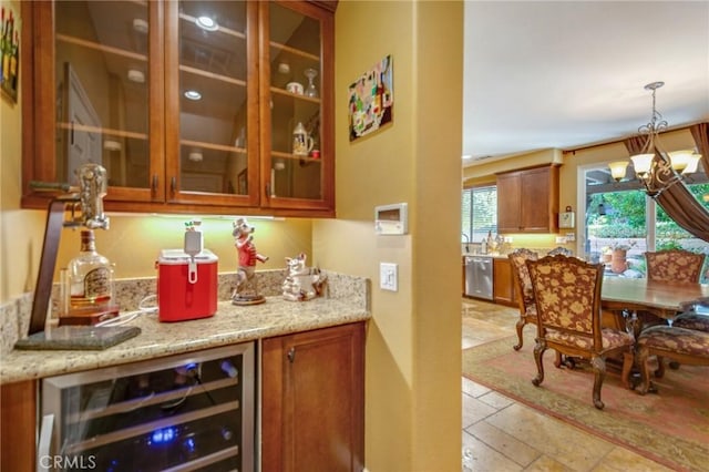 bar featuring dishwasher, beverage cooler, light stone counters, a chandelier, and decorative light fixtures