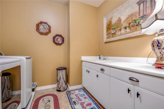 washroom featuring sink, light tile patterned floors, cabinets, and independent washer and dryer