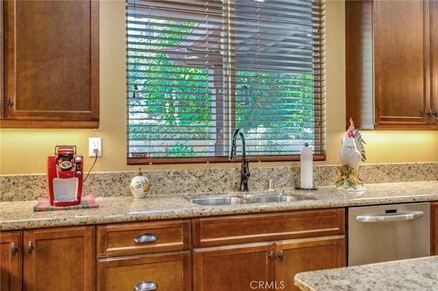 kitchen with light stone counters, stainless steel dishwasher, plenty of natural light, and sink