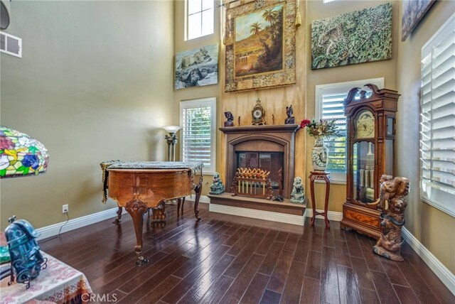 sitting room with a high ceiling, a healthy amount of sunlight, and dark hardwood / wood-style floors