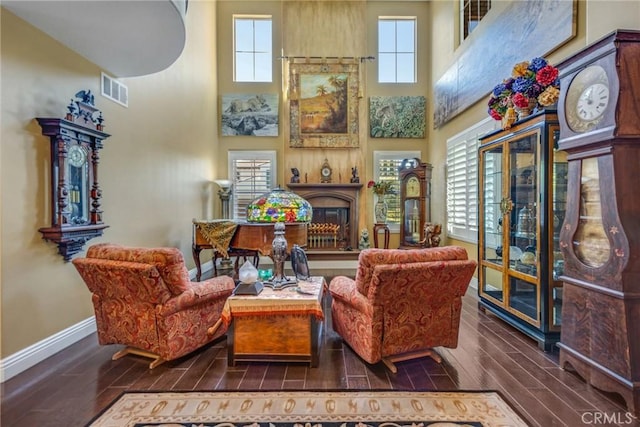 sitting room featuring a towering ceiling, dark hardwood / wood-style flooring, and plenty of natural light