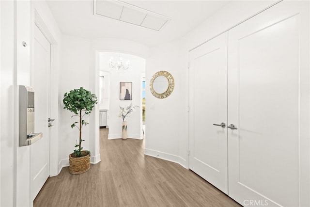 hall featuring light wood-type flooring and an inviting chandelier