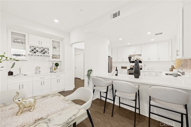 kitchen featuring sink, dark hardwood / wood-style floors, decorative backsplash, appliances with stainless steel finishes, and white cabinetry