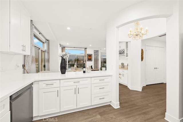 kitchen with white cabinets, hanging light fixtures, stainless steel dishwasher, dark hardwood / wood-style flooring, and a chandelier