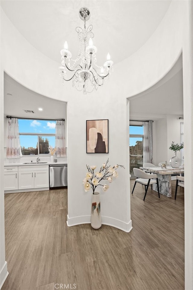 dining space with hardwood / wood-style flooring, a wealth of natural light, a notable chandelier, and sink