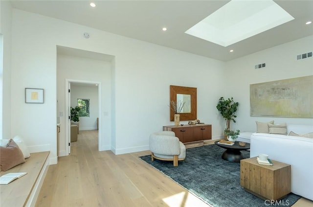 living area featuring a skylight and light hardwood / wood-style flooring