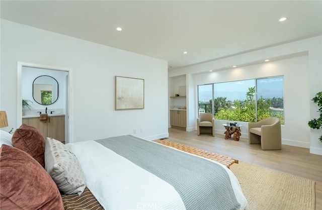 bedroom with light hardwood / wood-style floors and ensuite bath