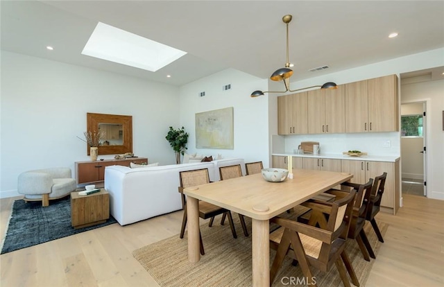 dining space with a skylight and light wood-type flooring