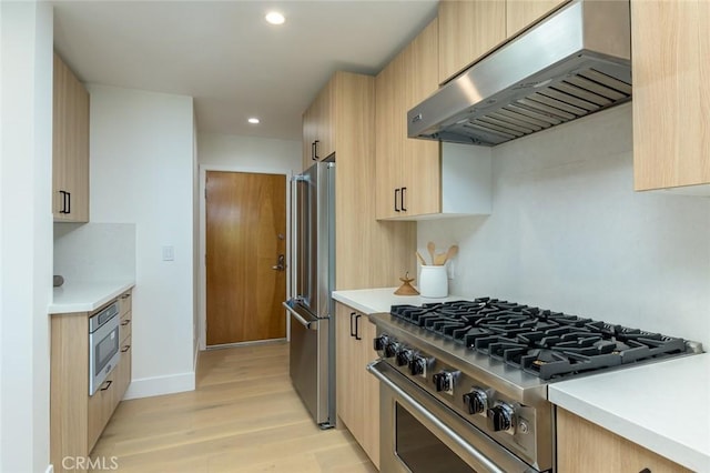 kitchen featuring light brown cabinets, light wood-type flooring, stainless steel appliances, and extractor fan