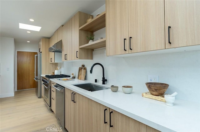 kitchen with light brown cabinets, sink, range hood, and a skylight