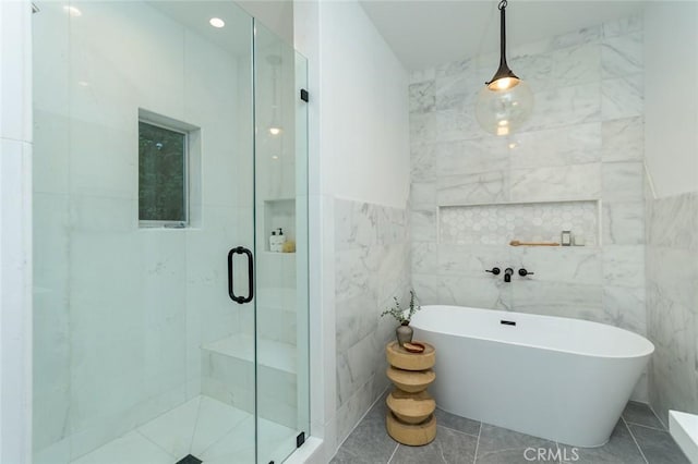 bathroom featuring tile patterned flooring, independent shower and bath, and tile walls