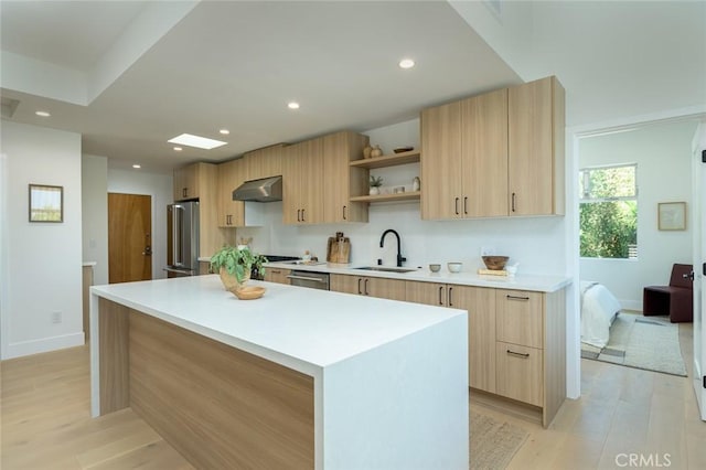 kitchen with a center island, exhaust hood, sink, light hardwood / wood-style flooring, and appliances with stainless steel finishes