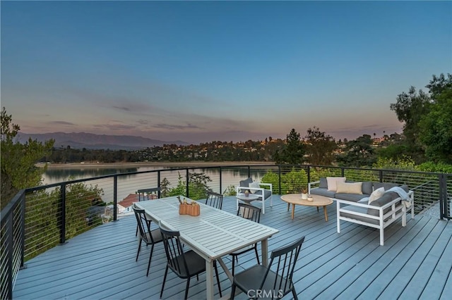 deck at dusk with a water view and an outdoor hangout area