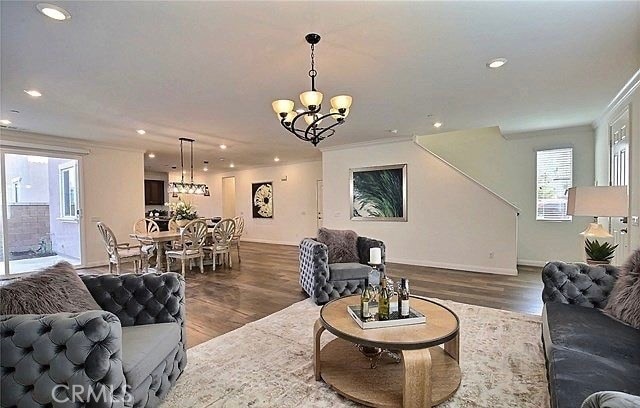 living room with ornamental molding, an inviting chandelier, and dark hardwood / wood-style floors