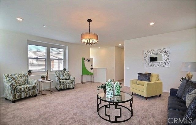 carpeted living room with a chandelier