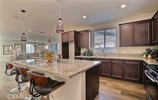 kitchen featuring a kitchen island, stainless steel range, pendant lighting, and light wood-type flooring