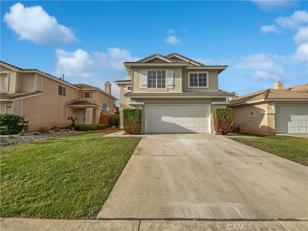 view of property featuring a garage and a front lawn