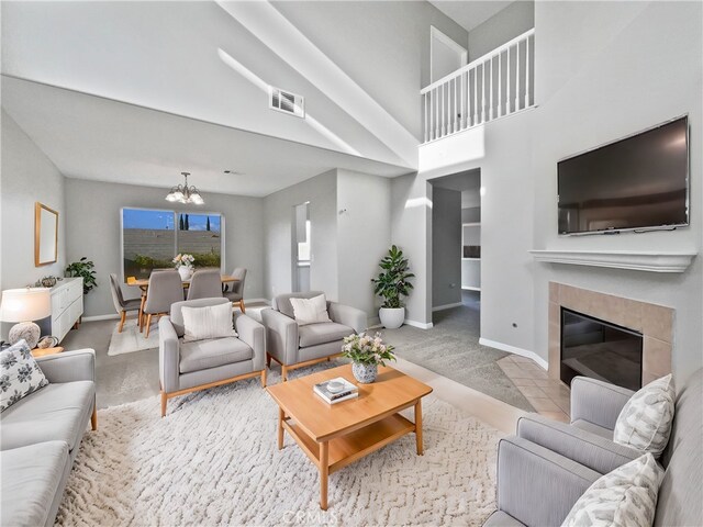 living room with carpet floors, a tiled fireplace, and a chandelier