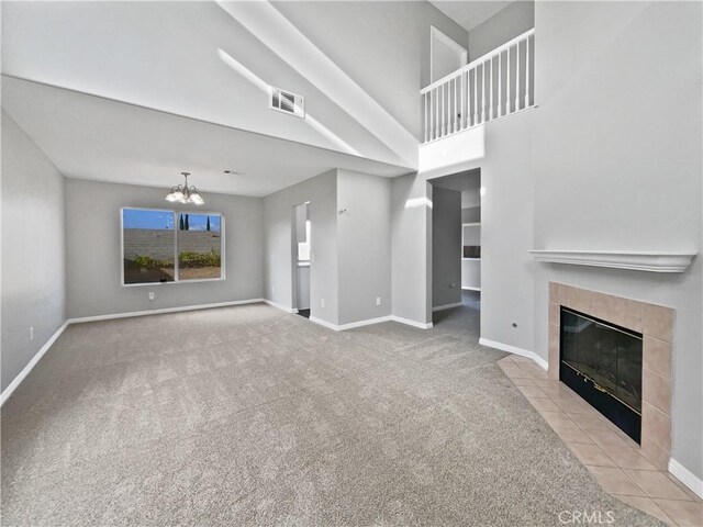 unfurnished living room featuring light colored carpet, a fireplace, and an inviting chandelier