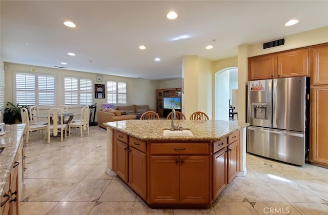 505 Lowe Dr, Placentia, CA 92870 - kitchen featuring stainless steel fridge, arched walkways, recessed lighting, a center island, and light stone countertops