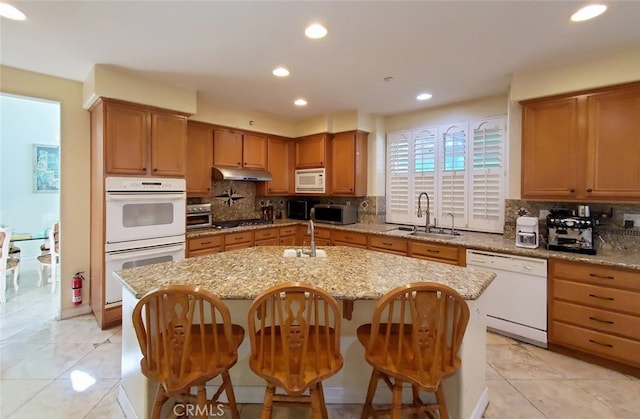 505 Lowe Dr, Placentia, CA 92870 - kitchen featuring white appliances, under cabinet range hood, tasteful backsplash, a center island with sink, and light tile patterned floors