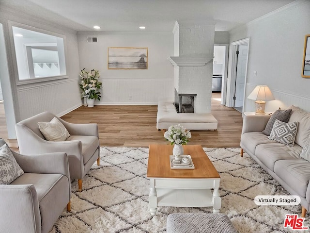 living room featuring a fireplace, light wood-type flooring, and crown molding