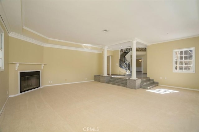 unfurnished living room with a glass covered fireplace, carpet floors, crown molding, decorative columns, and baseboards