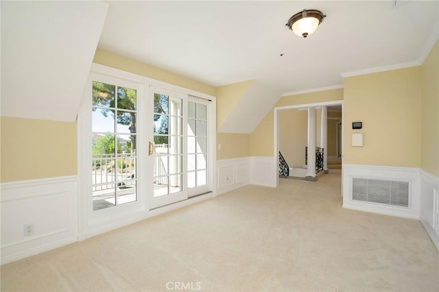 interior space featuring visible vents, light carpet, lofted ceiling, and wainscoting