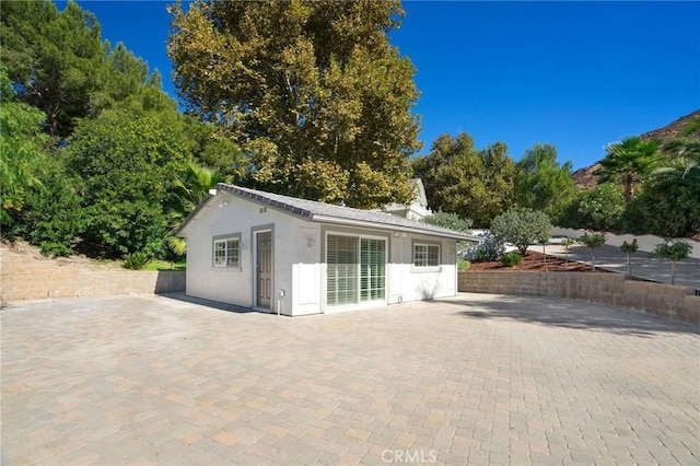 rear view of property featuring a patio and an outbuilding