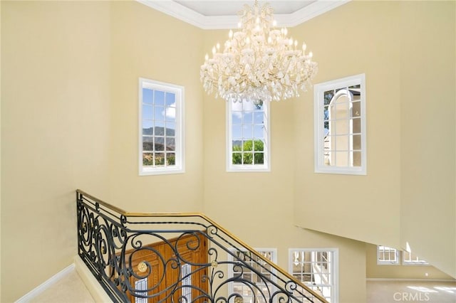 stairway featuring baseboards, an inviting chandelier, ornamental molding, and a towering ceiling