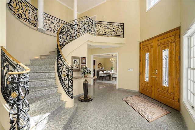 entryway featuring a notable chandelier, a high ceiling, speckled floor, and baseboards