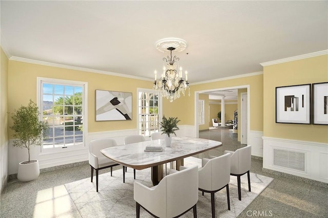 dining room featuring crown molding, a notable chandelier, visible vents, and wainscoting