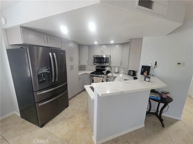 kitchen featuring kitchen peninsula, light tile patterned floors, a textured ceiling, gray cabinetry, and stainless steel appliances