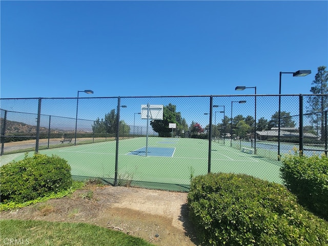 view of tennis court featuring basketball hoop