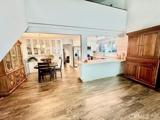 kitchen with kitchen peninsula, appliances with stainless steel finishes, a towering ceiling, and dark wood-type flooring