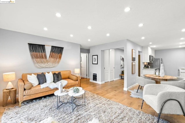 living room with heating unit and light hardwood / wood-style flooring