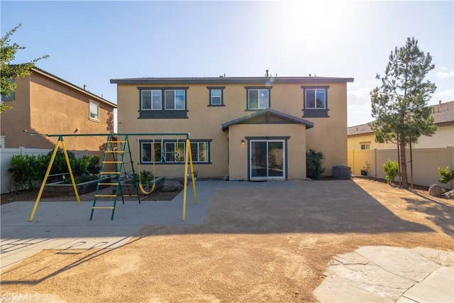 back of property featuring a playground, central air condition unit, and a patio