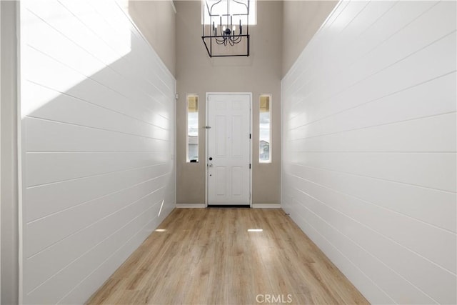 entryway featuring a chandelier, a high ceiling, and light wood-type flooring