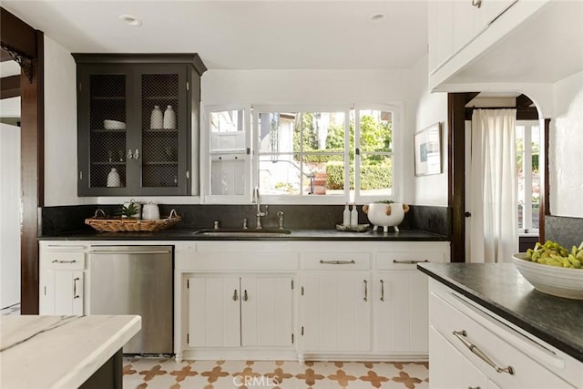 kitchen with stainless steel dishwasher, white cabinetry, and sink