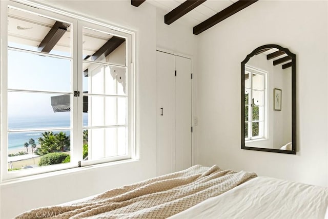 unfurnished bedroom with lofted ceiling with beams and a water view