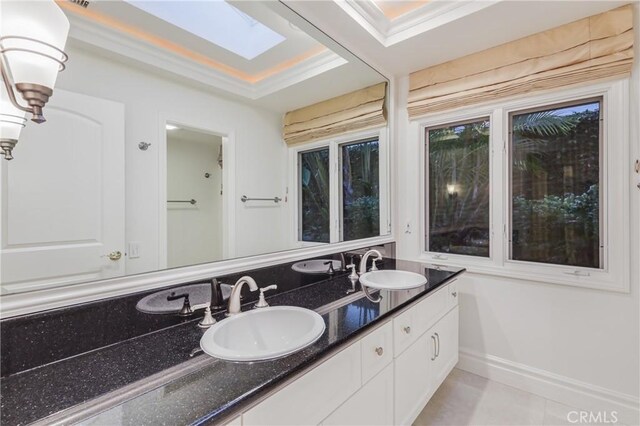 bathroom with a tray ceiling, a skylight, and vanity