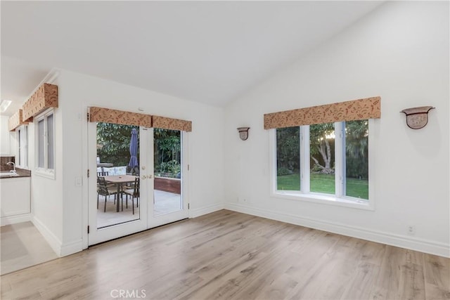 interior space with light hardwood / wood-style flooring, high vaulted ceiling, and french doors