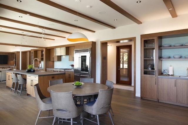 dining area with beamed ceiling, sink, and dark wood-type flooring