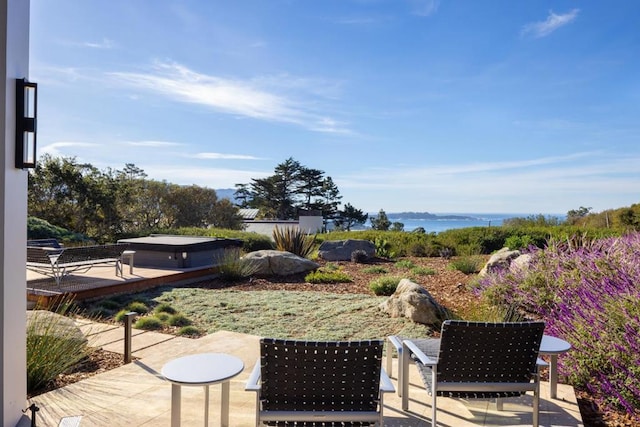 view of patio with a water view and a hot tub