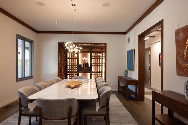 dining space with a chandelier, ornamental molding, and dark wood-type flooring