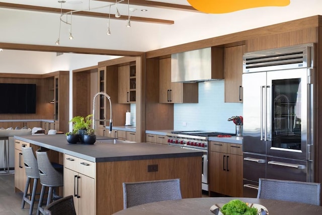 kitchen with sink, a center island, wall chimney exhaust hood, premium appliances, and decorative backsplash