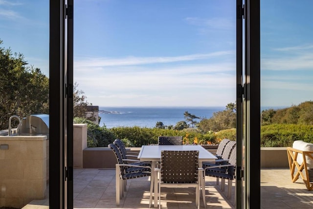 balcony featuring a water view, a patio area, and exterior kitchen