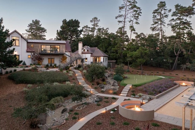 back house at dusk featuring a fire pit and a balcony